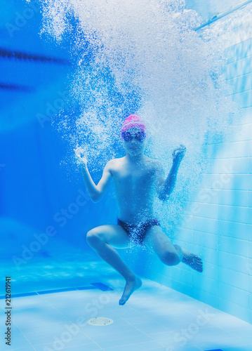 a little boy is having fun under water, tumbling and grimacing, making faces
