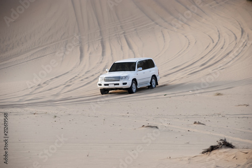 Luxurous white SUW 4x4 on desert safari on dunes exreme racing in arabia travel rally on sand in sports vehicle all wheel drive