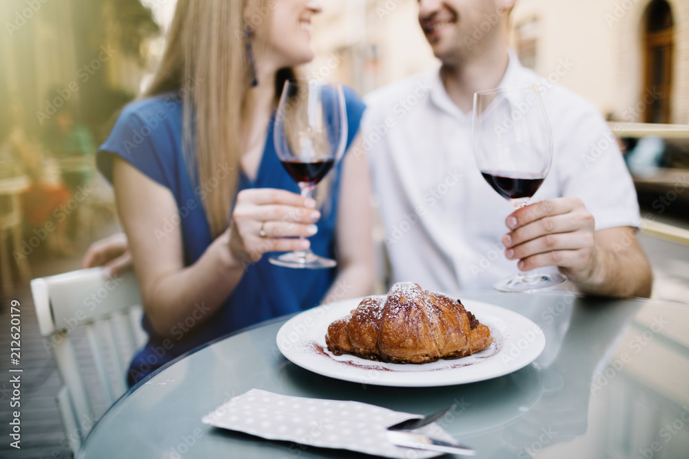 Cheerful couple in a restaurant with glasses of red wine. Young couple with glasses of red wine in a restaurant with city view Cheerful couple in a restaurant with glasses of red wine. Young couple with glasses of red wine in a restaurant with city view