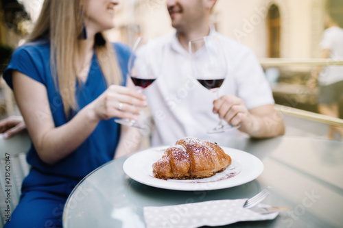 Cheerful couple in a restaurant with glasses of red wine. Young couple with glasses of red wine in a restaurant with city view