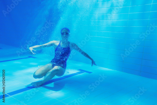 beautiful young girl with a good figure swims under water, effectively dives
