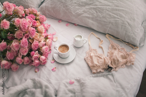 Fototapeta Naklejka Na Ścianę i Meble -  Gently pink roses lie on the gray linen bedding with coffee. Romantic mood of the morning