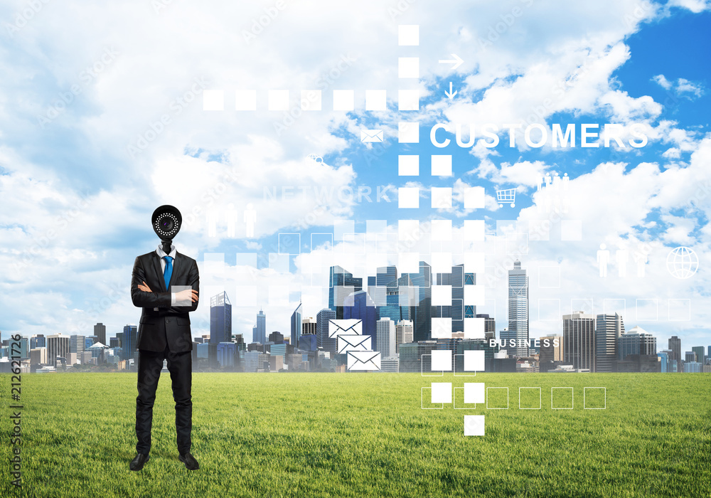 Camera headed man standing on green grass against modern cityscape Camera headed man standing on green grass against modern cityscape