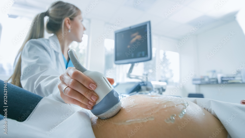In the Hospital, Close-up Shot of the Doctor does Ultrasound / Sonogram Procedure to a Pregnant Woman. Obstetrician Moving Transducer on the Belly of the Future Mother. In the Hospital, Close-up Shot of the Doctor does Ultrasound / Sonogram Procedure to a Pregnant Woman. Obstetrician Moving Transducer on the Belly of the Future Mother.
