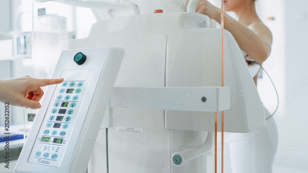 In the Hospital, Mammography Technologist / Doctor Pushes Button on Mammogram Machine Activating Female Patient Scan. Friendly Doctor Explains Importance of Breast Cancer Prevention Screening. In the Hospital, Mammography Technologist / Doctor Pushes Button on Mammogram Machine Activating Female Patient Scan. Friendly Doctor Explains Importance of Breast Cancer Prevention Screening.