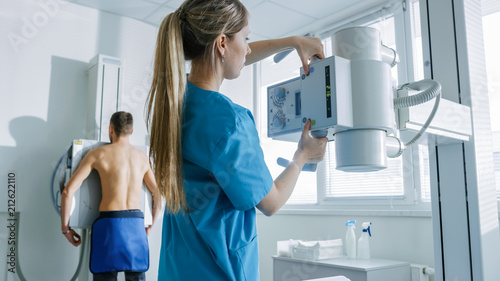 In the Hospital, Man Standing Face Against the Wall While Medical Technician Adjusts X-Ray Machine For Scanning. Scanning for Fractures, Broken Limbs, Chest, Cancer or Tumor. Modern Hospital photo
