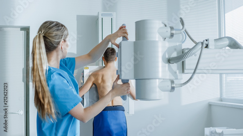 In the Hospital, Man Standing Face Against the Wall While Medical Technician Adjusts X-Ray Machine For Scanning. Scanning for Fractures, Broken Limbs, Chest, Cancer or Tumor. Modern Hospital photo