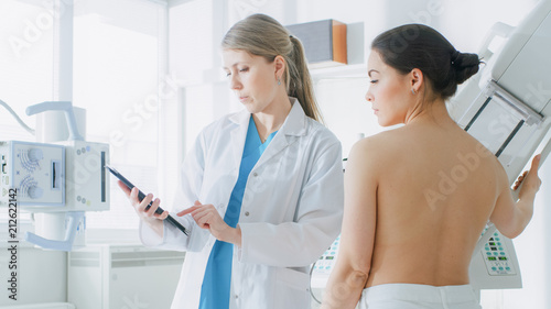 In the Hospital, Mammography Technologist / Doctor adjusts Mammogram Machine for a Female Patient. Friendly Doctor Explains Importance of Breast Cancer Prevention Screening. Modern Clinic. photo