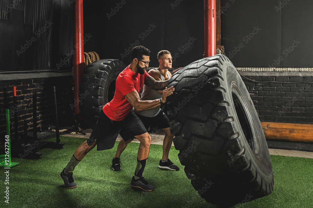 Two strong men doing a tire flip exercise Stock Photo Adobe Stock