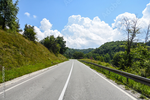 Mountain road. Old road through the forest. Concept of travel under a blue sky