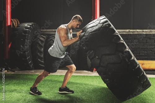 Strong sportsman doing  a tire flip exercise