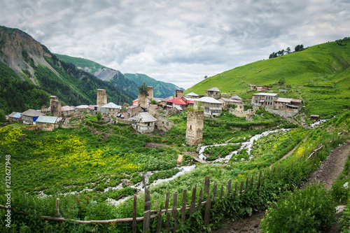 Village of Adishi in Svaneti, Georgia. View of mountain village in Caucasus mountains with ancient Svan towers and mountain streams. Houses on hills with green grass. Traditional Georgian Village. photo
