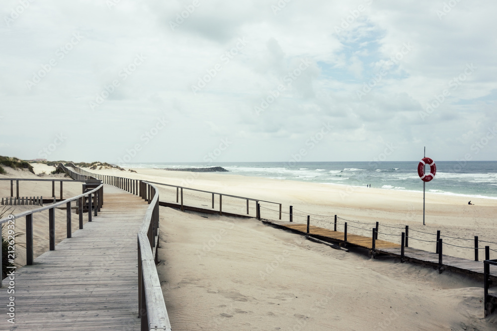 Wooden footbridge of Costa Nova beach, Aveiro, Portugal. With life buoy.