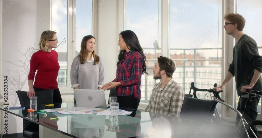 Learning group of students high fiving each other behind a glas desk