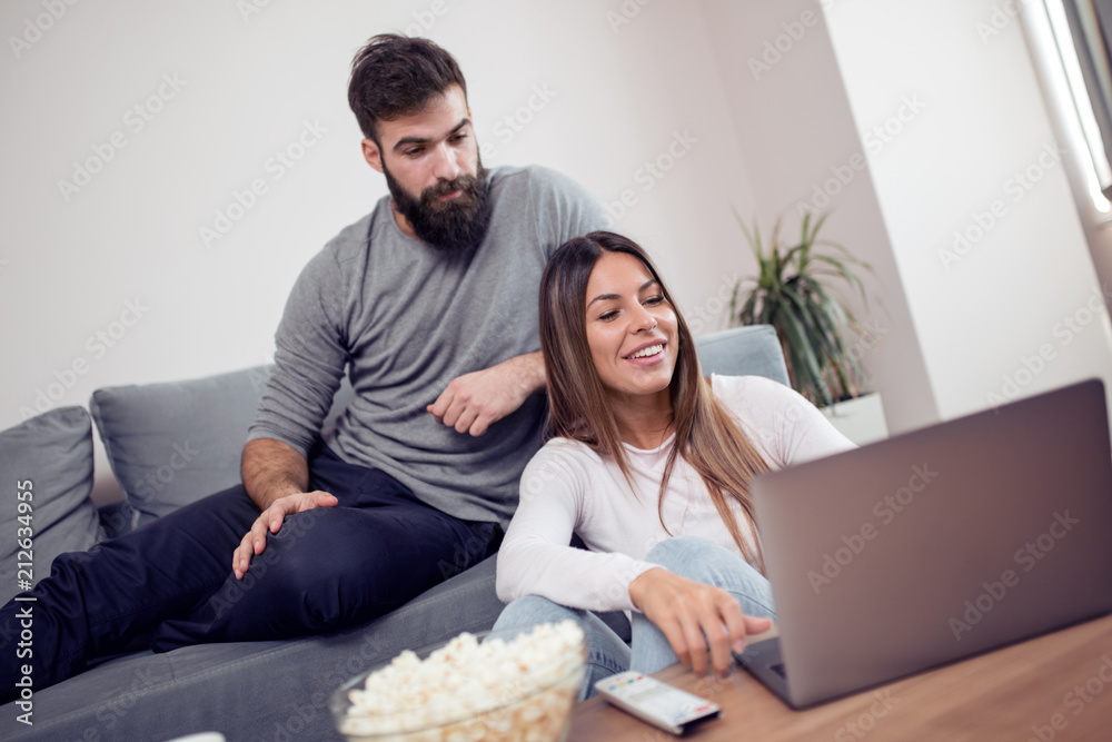 Young couple relaxing on sofa with laptop Young couple relaxing on sofa with laptop