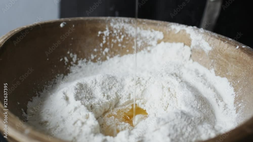 Slow motion shot of egg falls on wooden bowl with flour. Slow motion shot of egg falls on wooden bowl with flour.