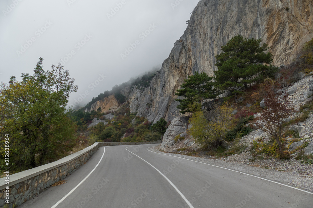 Winding mountain road on cloudy day / Winding mountain road in fog on cloudy day