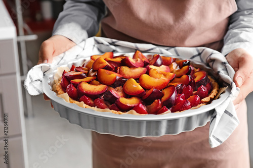 Woman holding delicious pie with plums, closeup