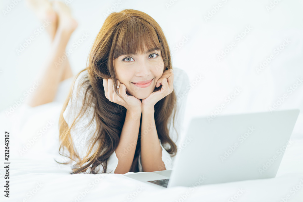 Smile Teenage girl lying on bed using laptop Smile Teenage girl lying on bed using laptop