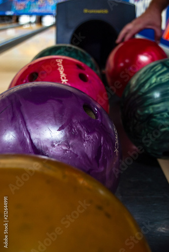 Bowling balls lined up and wooden lane in bowling hall
