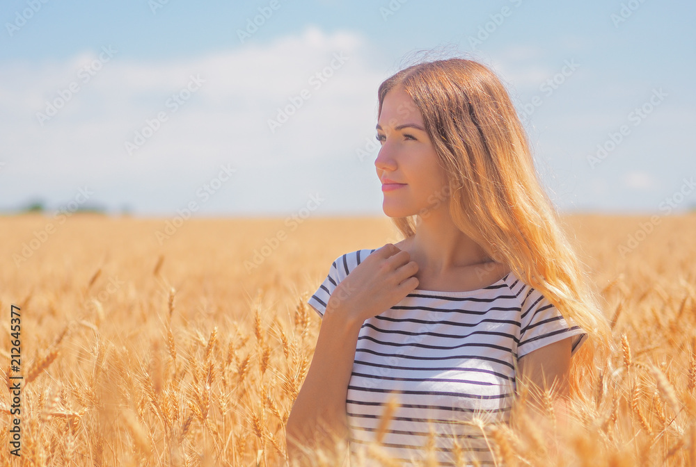 Young woman at the wheat field under the blue sky at the sunny day Young woman at the wheat field under the blue sky at the sunny day