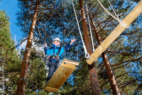 A kid evolves through an obstacle hanging from the trees at an adventure park in Segovia, Spain