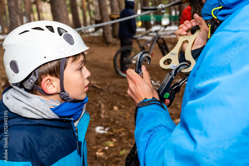 A kid receives safety instructions before going through an obstacle trail hanging from the trees at an adventure park in Segovia, Spain