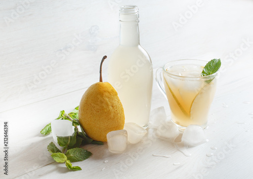 Pear cider. A glass and a bottle of pear organic vinegar with ice cubes and mint photo