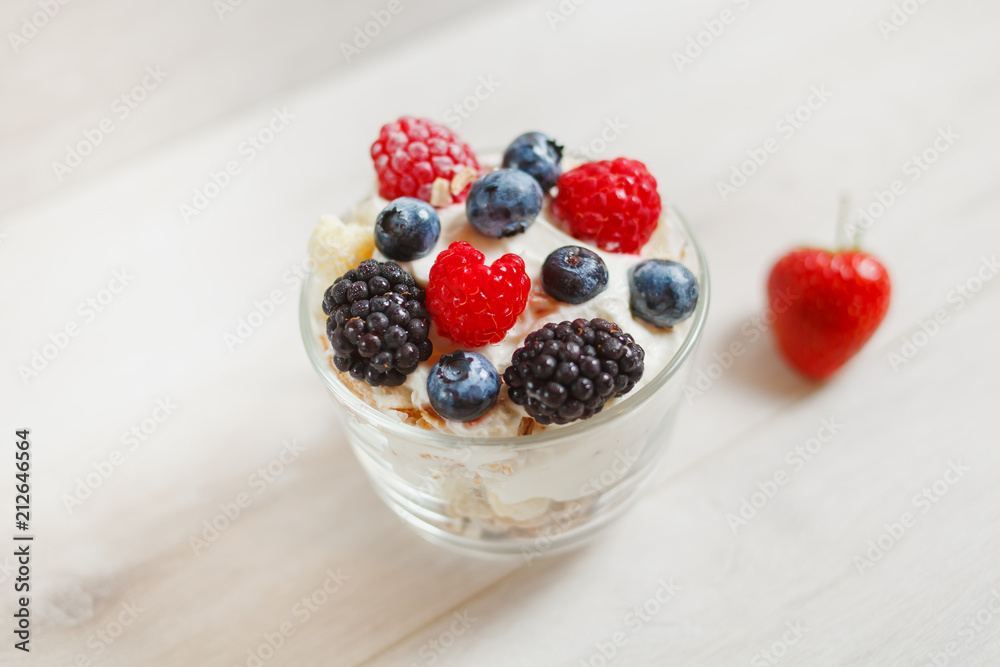 Granola with yogurt in glass and berries, strawberries, blackberries, blueberries, raspberries.