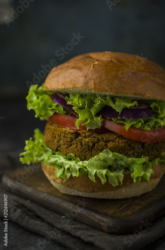 Vegan burger with vegetables on cutting board