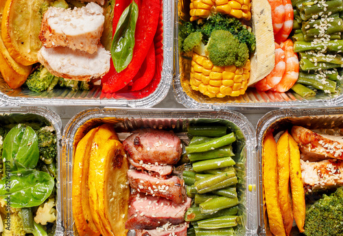Healthy meal prep containers with vegetables, chicken, beef and shrimp grilled. Close-up, view top.