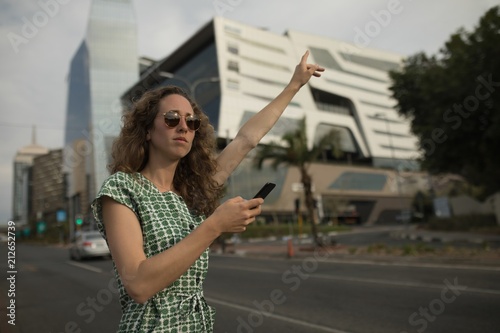 Woman hailing for ride with mobile phone in hand