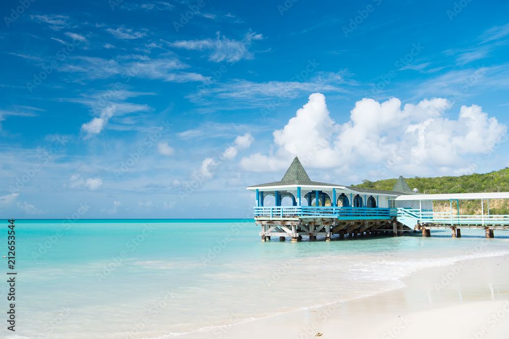Fototapeta premium Come and stay. Sea turquoise calm and bungalow terrace on water. Vacation sea sand beach cozy tropical house bungalow st.johns antigua. Idyllic sunny day at seaside blue sky. Paradise sea resort