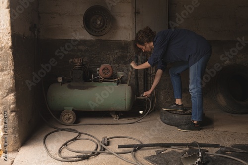 Female worker using portable spray paint machine photo