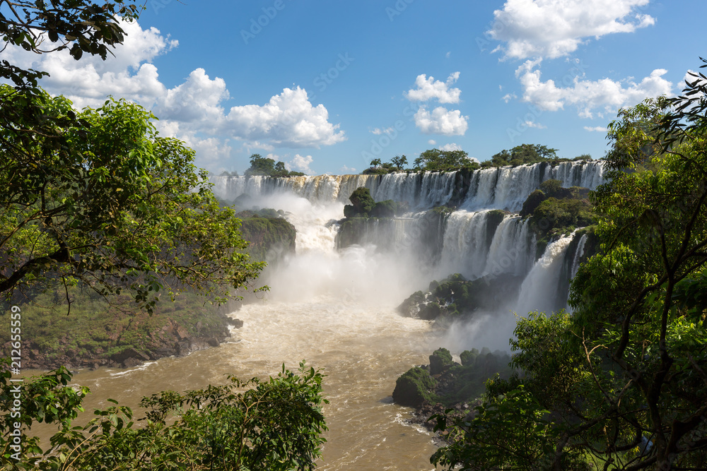 Obraz premium Waterfalls at Iguazu falls framed by trees and blue sky