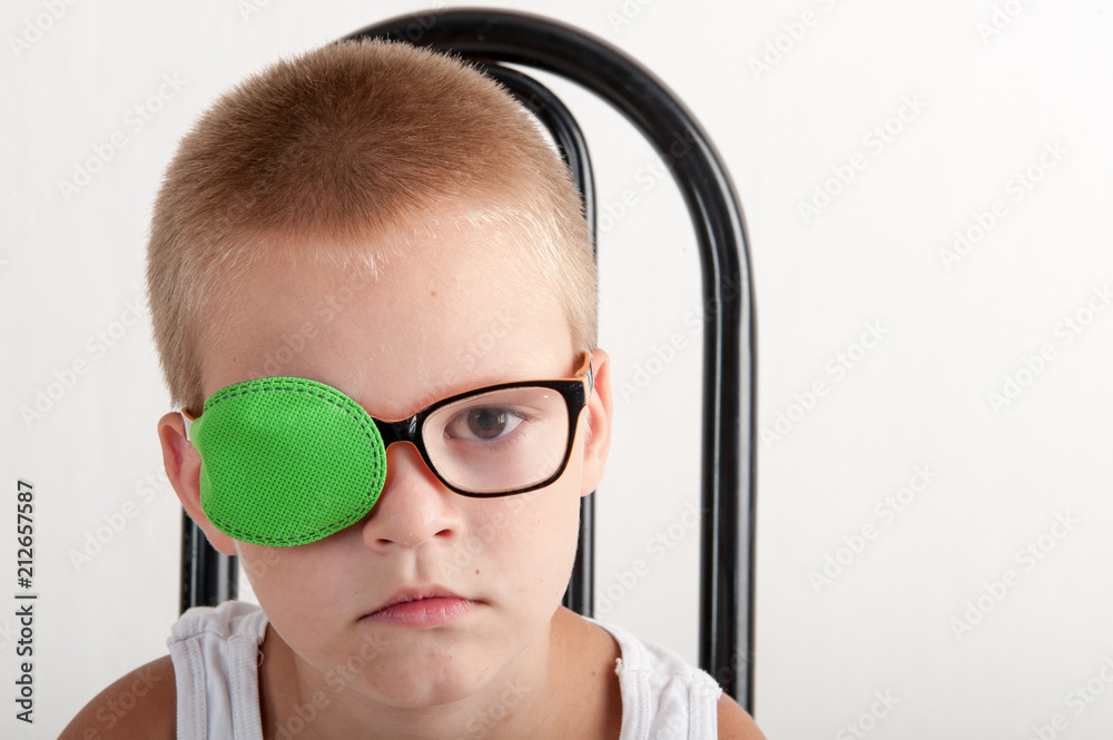 Child in glases with green Occluder. Ortopad Boys Eye Patces nozzle for  glasses for treating strabismus (