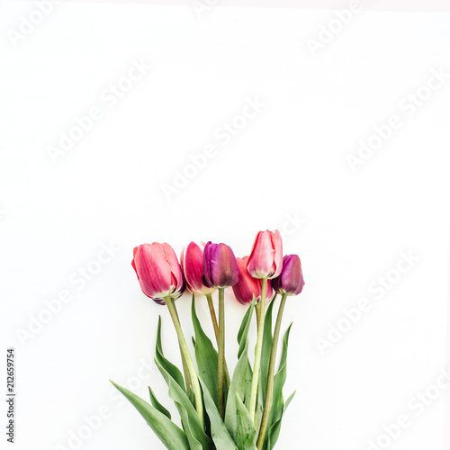 Fototapeta Naklejka Na Ścianę i Meble -  Woman hand holding tulips bouquet on white. Flat lay, top view flowers festive background.