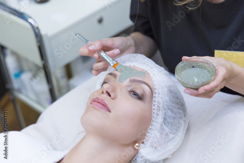 Young beautiful girl receiving facial mask from doctor in spa beauty salon - indoors photo