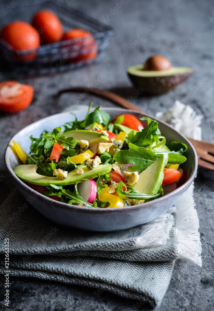 Healthy arugula salad with avocado, radish, bell pepper, tomato and Roquefort cheese