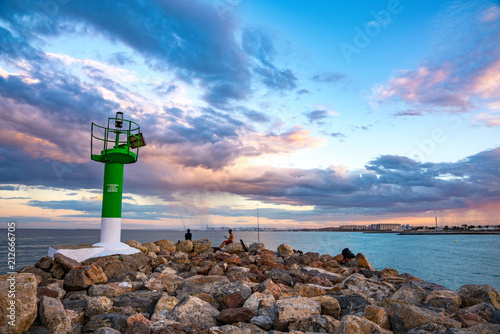 View of the lighthouse at the entrance to Port Saplaya Bay during a colorful sunset. Valencia