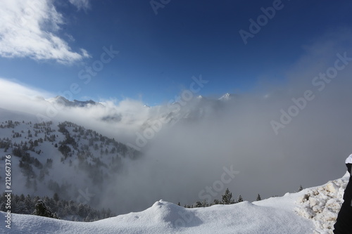 the top of the mountains with forest covered with snow, fog and clouds on a sunny frosty day