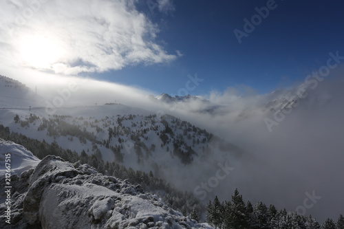 the top of the mountains with forest covered with snow, fog and clouds on a sunny frosty day