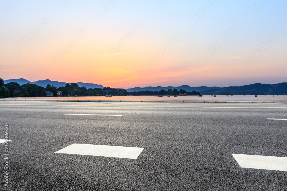 Fototapeta premium Empty asphalt road and hills silhouette at sunset