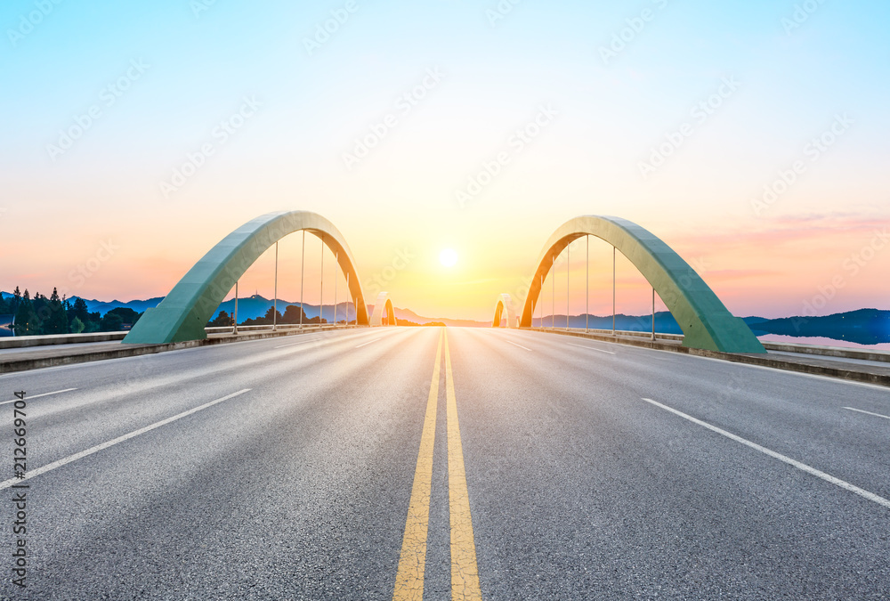 Obraz premium Pusta droga asfaltowa i most o zachodzie słońca
