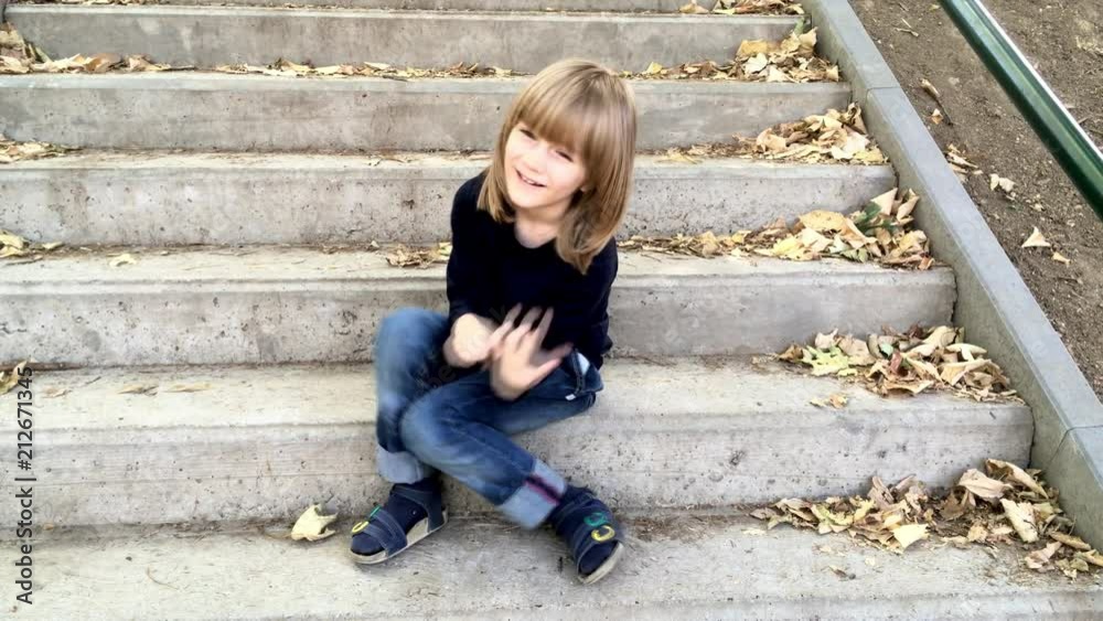 Boy is laughing, sitting on the stairs in the park, 4k video Boy is laughing, sitting on the stairs in the park, 4k video