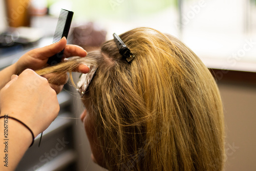 Blonde woman receiving haircut at a salon. Woman with blonde highlights. Hair foils on a female client. Master stylist cutting hair