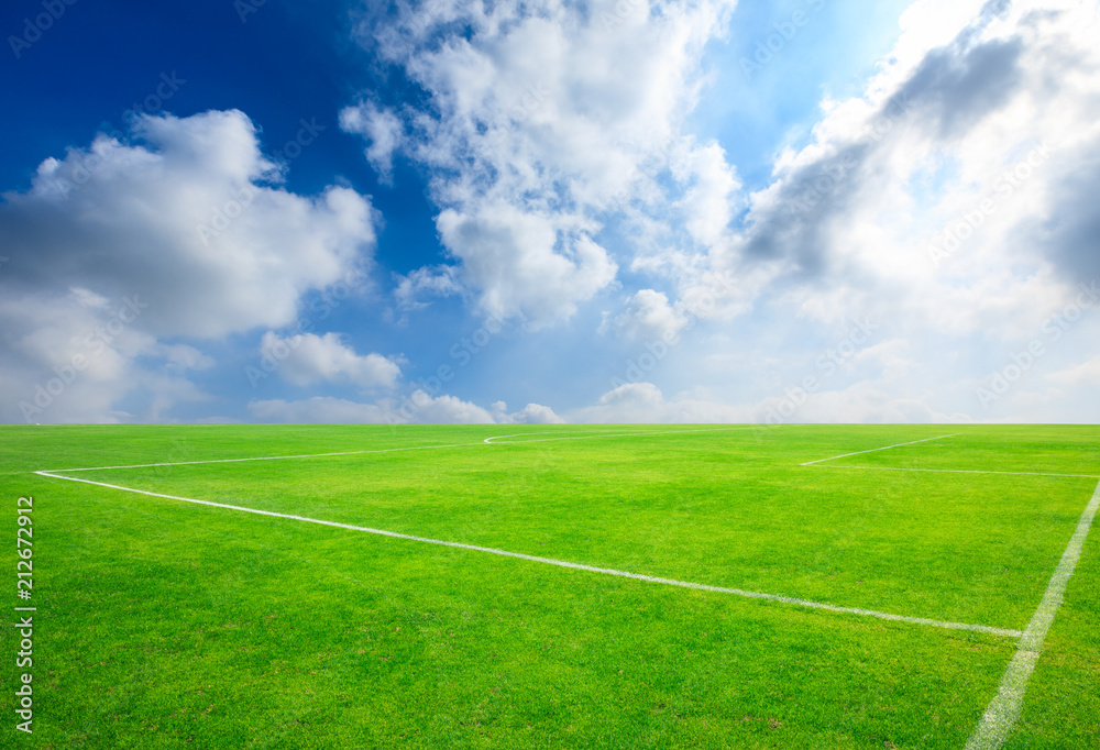 Green football field under blue sky background