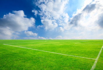 Green football field under blue sky background