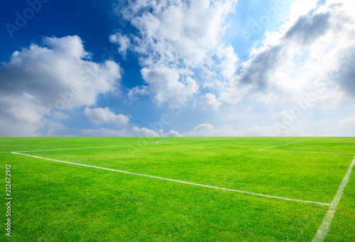 Green football field under blue sky background © ABCDstock