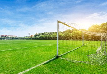 Green football field under blue sky background